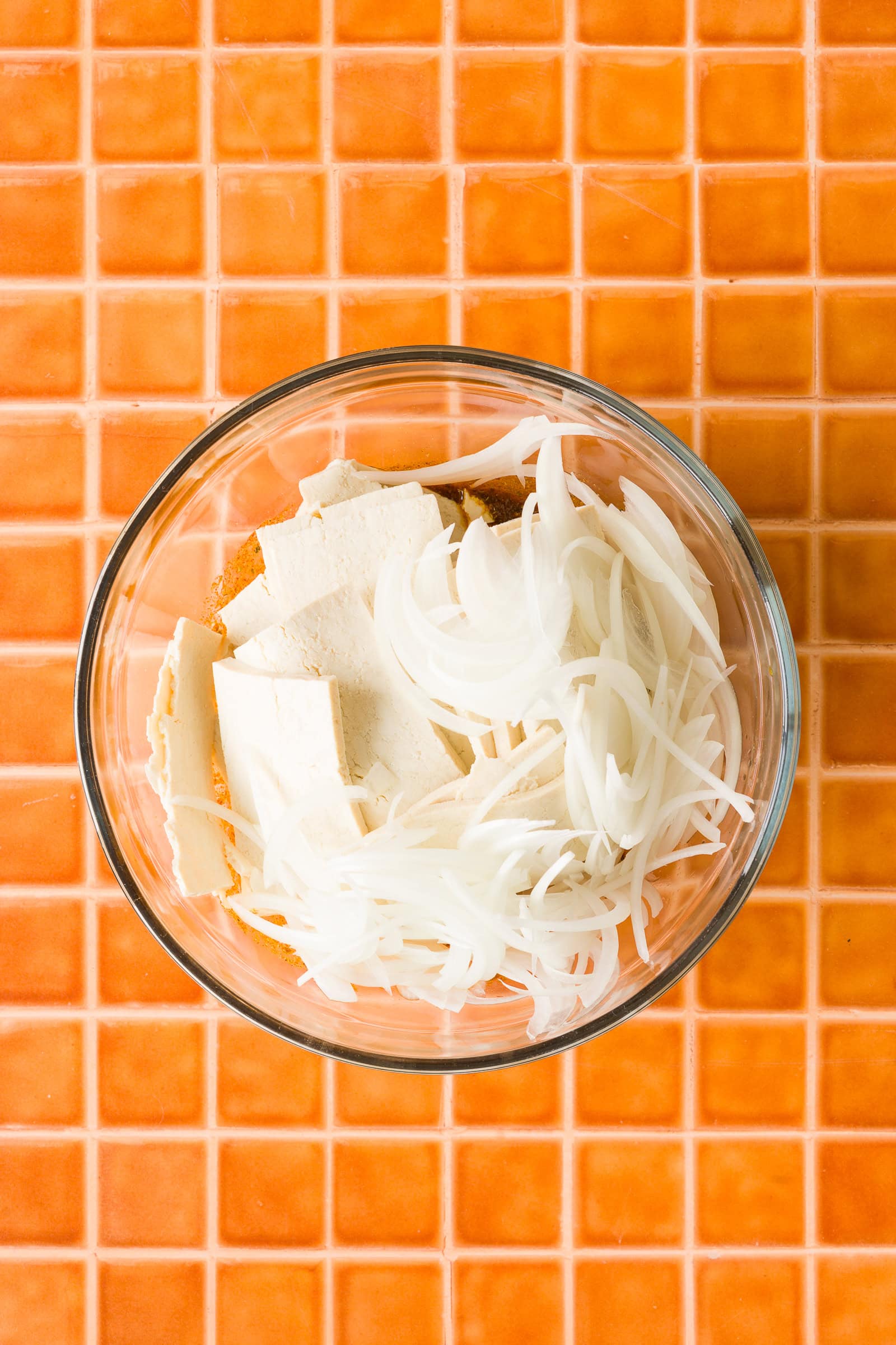 Adding thinly sliced tofu and onions to the shawarma marinade.