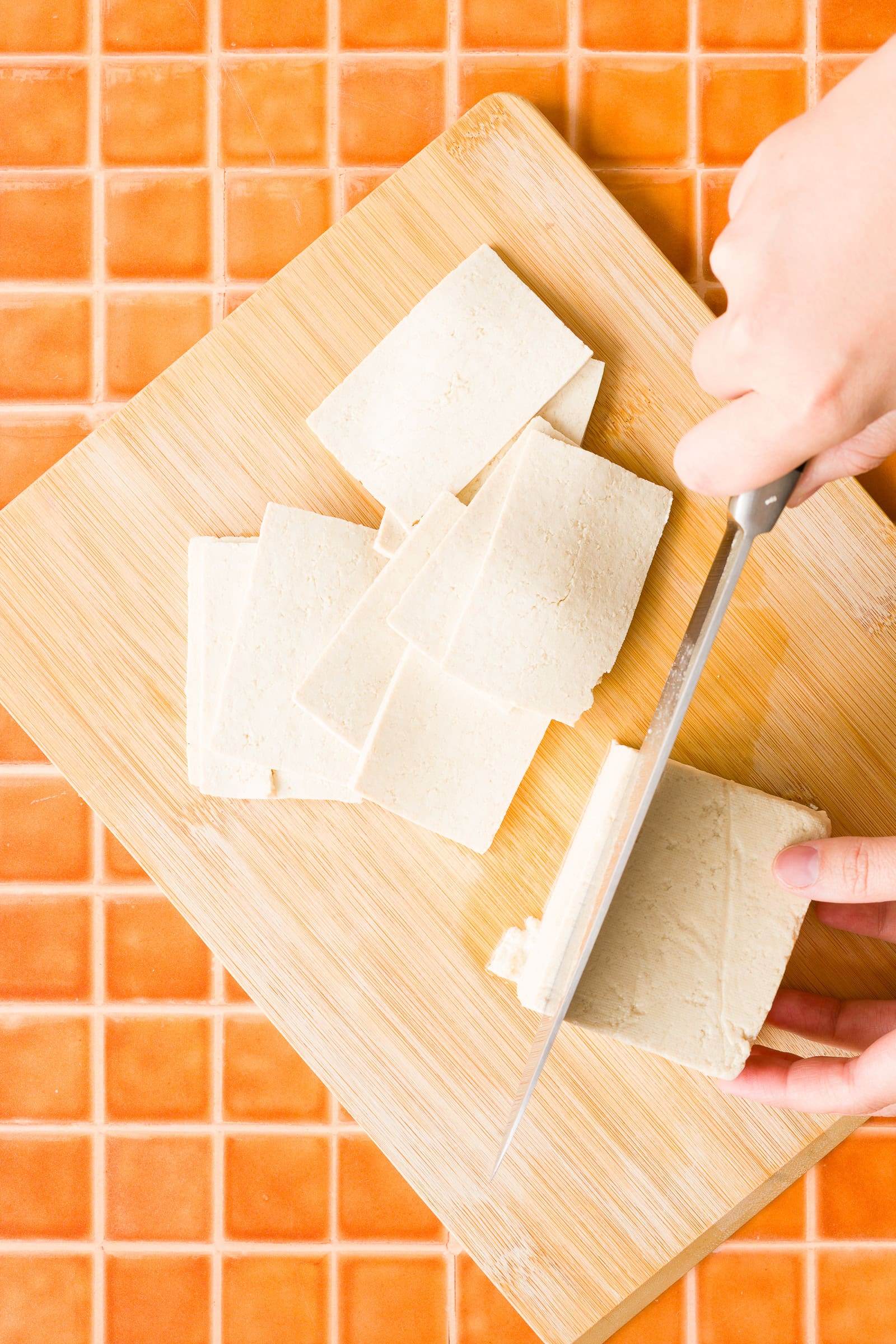Thinly slicing extra-firm tofu into strips for tofu shawarma.