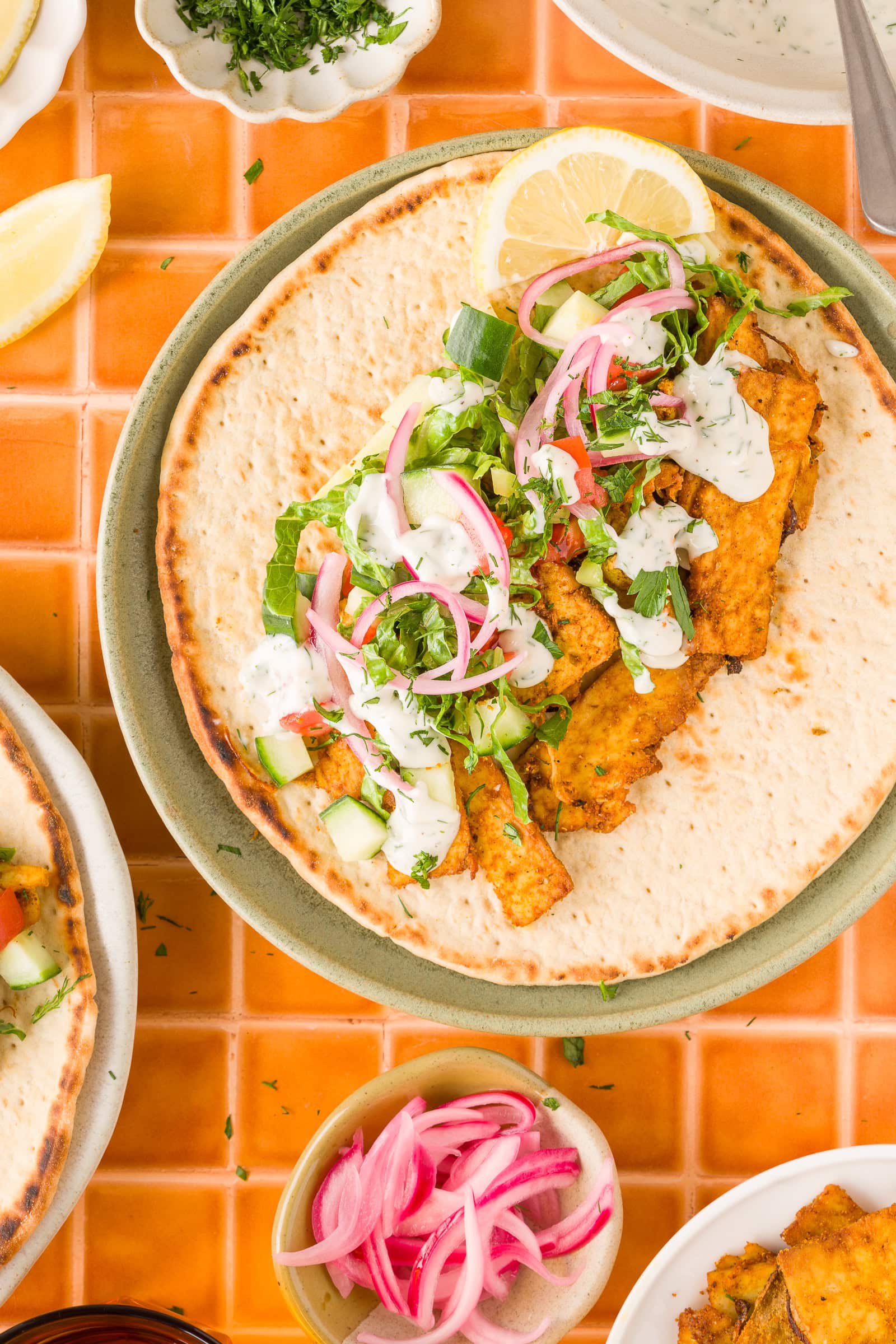Vegan tofu shawarma with roasted onions and creamy yogurt tahini sauce topped with vegetables.