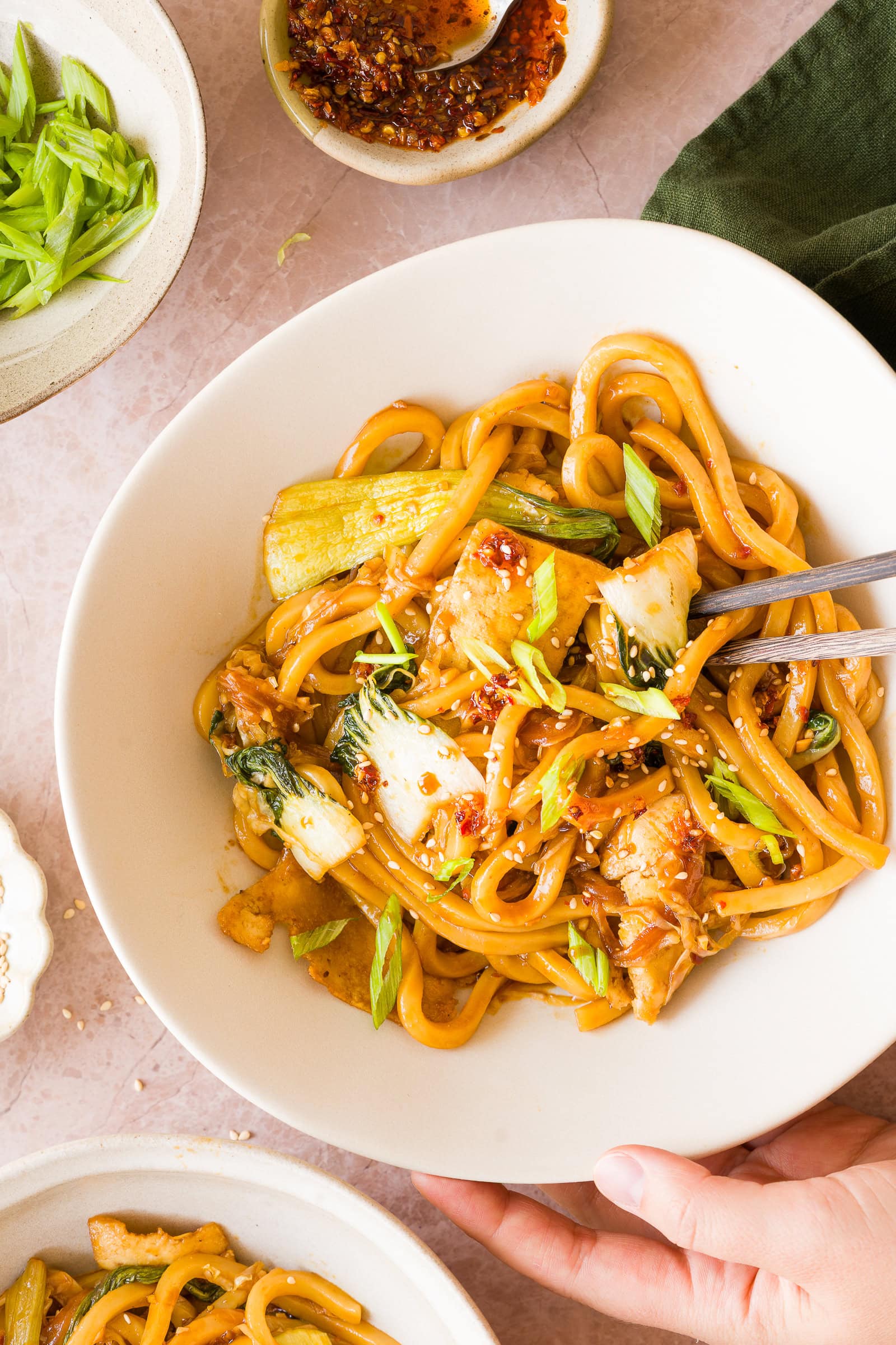 Close up chili garlic noodles in a bowl with green onions and sesame seeds.