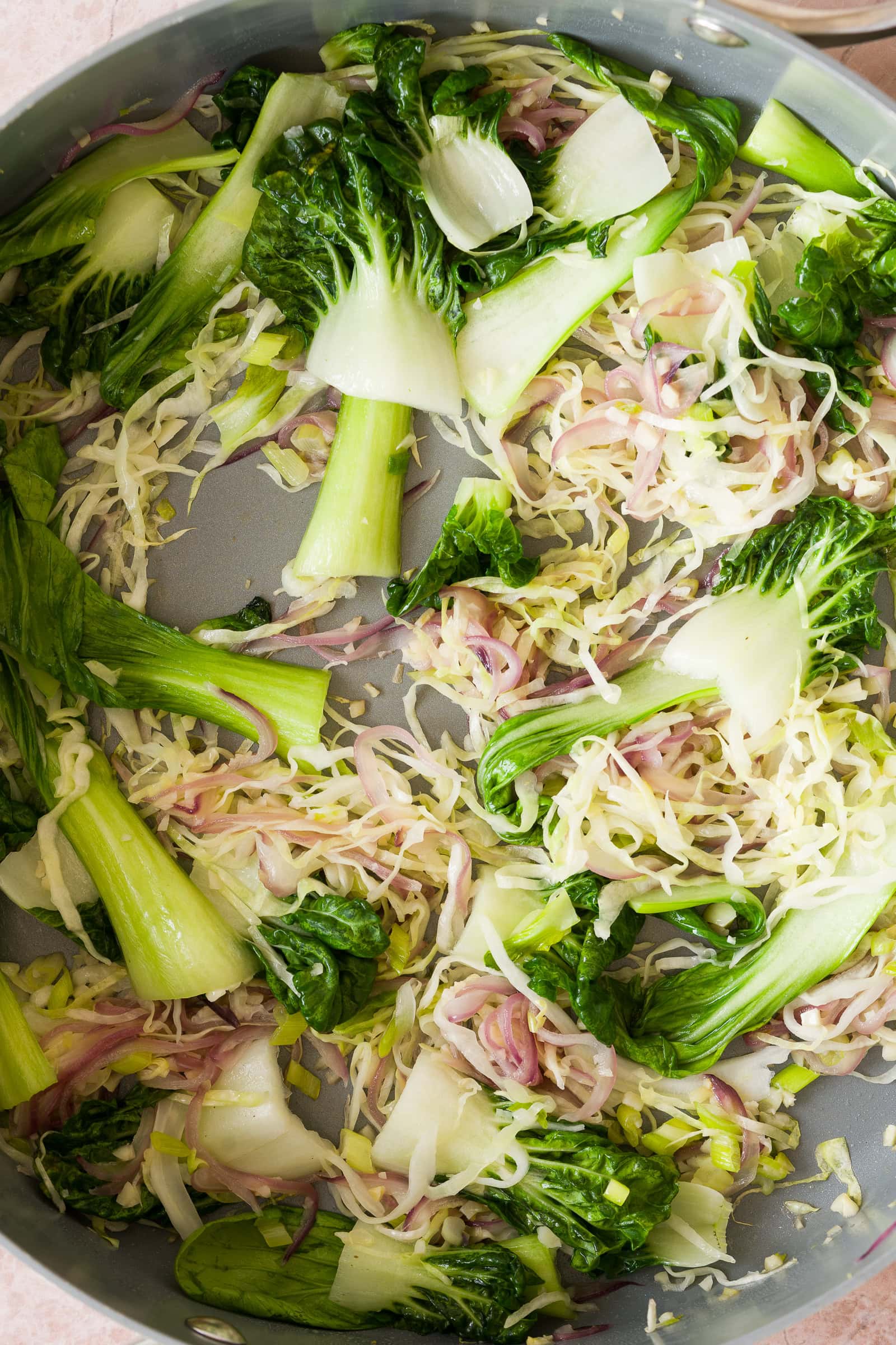 Cabbage and bok choy sautéing with red onion and garlic.