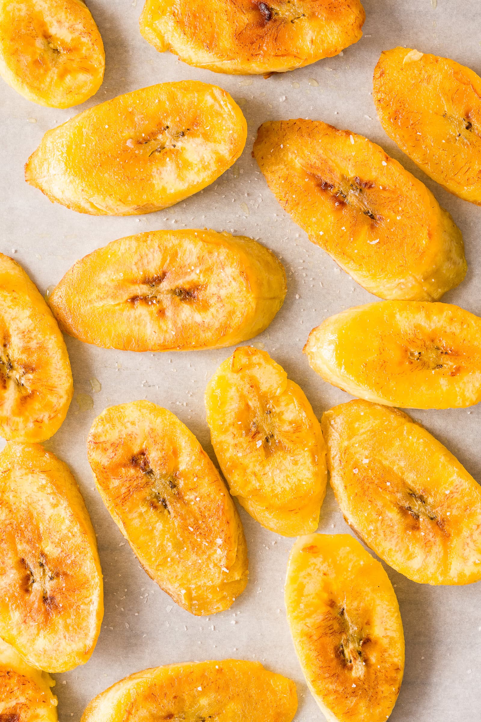 Browned plantains on a parchment-lined baking sheet.