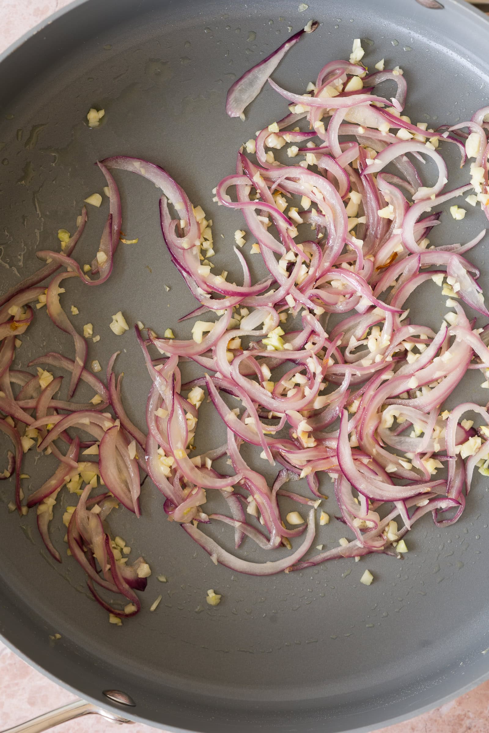 Red onion and garlic sautéing in a frying pan.