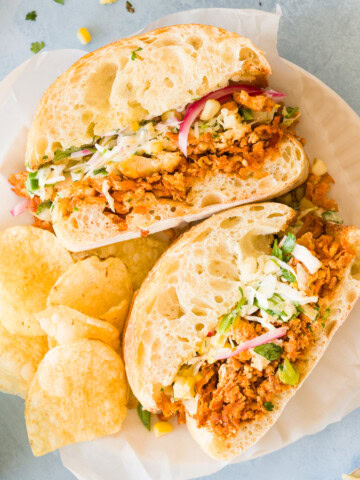 BBQ tofu sandwiches with shredded tofu, coleslaw, pickled red onions, and ranch served with potato chips.
