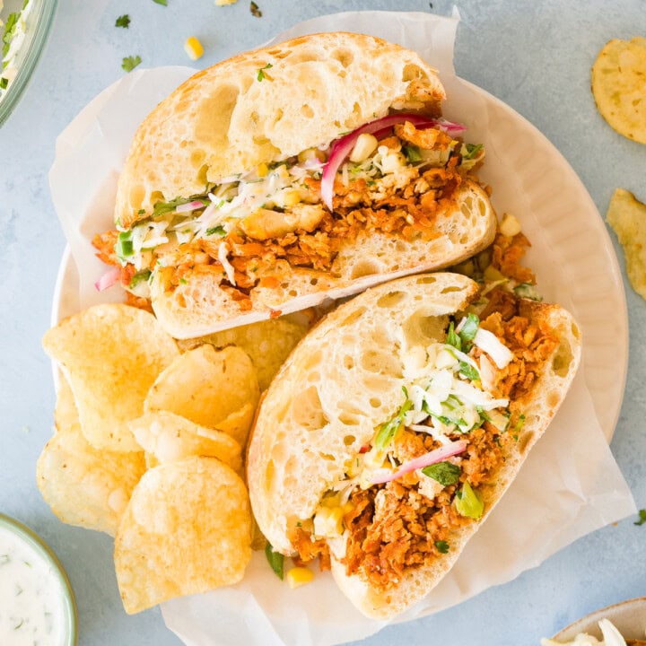 BBQ tofu sandwiches with shredded tofu, coleslaw, pickled red onions, and ranch served with potato chips.